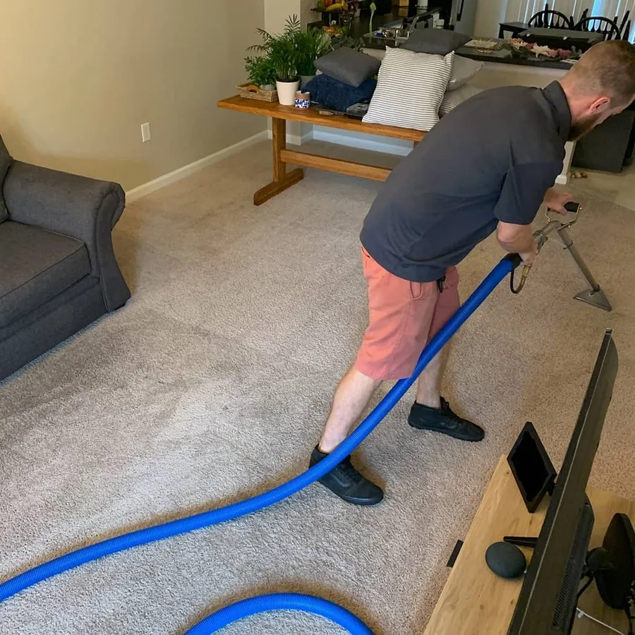 Bryan Wilson cleaning a living room carpet with truck-mount HWE equipment